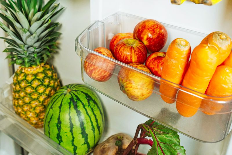 Fruits and vegetables being stored on the inside door of a refrigerator.