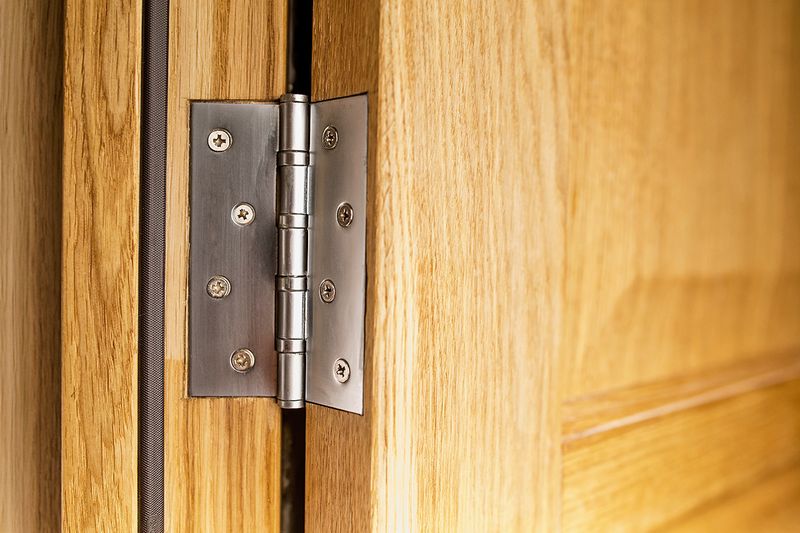 A close-up of a hinge on a wooden interior door.