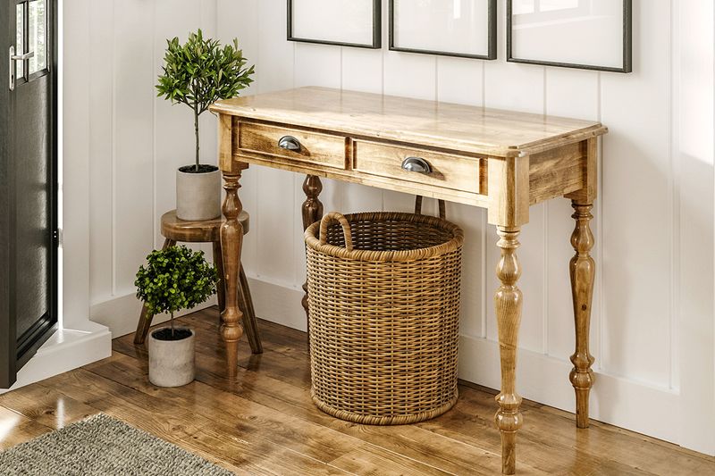 An entryway console with a large wicker basket underneath it and potted plants in the corner by the door.