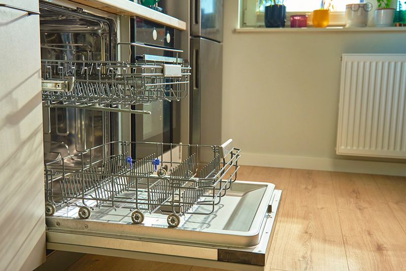 A clean, open dishwasher with nothing inside of it.