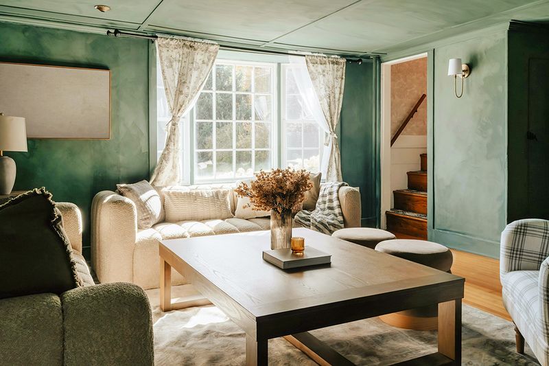 A living room color-drenched in a mid-tone shade of green, including the ceiling.