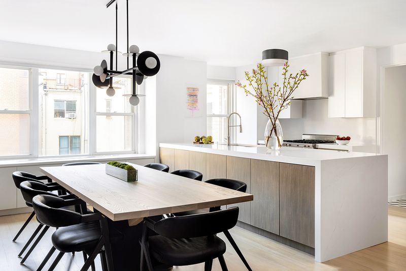 A modern, open-concept kitchen and dining space in a condo painted with Benjamin Moore Chantilly Lace.