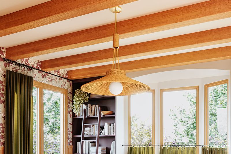 A close-up of a woven rattan pendant light hanging from a ceiling with exposed wooden beams.