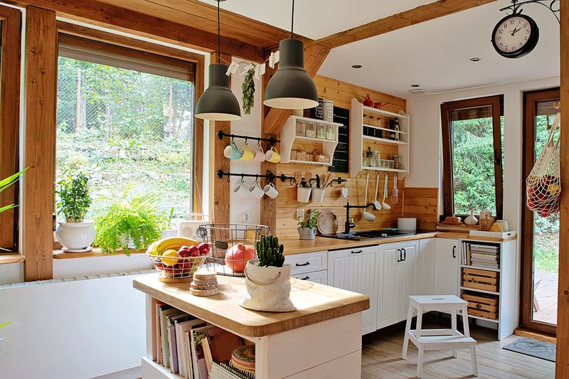 A rustic-looking kitchen with wood walls, white cabinets, wood countertops, and a few wood accessories.
