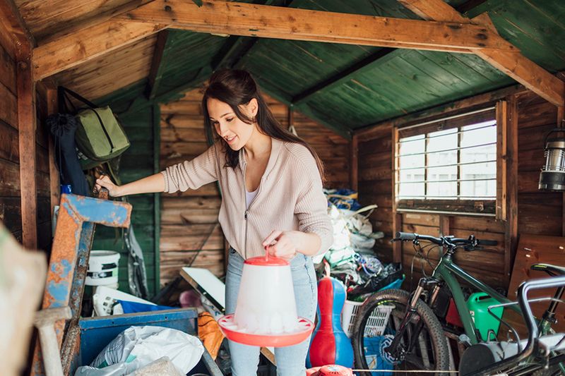 A young woman sorting through items in a cluttered attic.