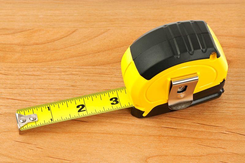 A yellow tape measure with a black rubber grip at the top of the casing.