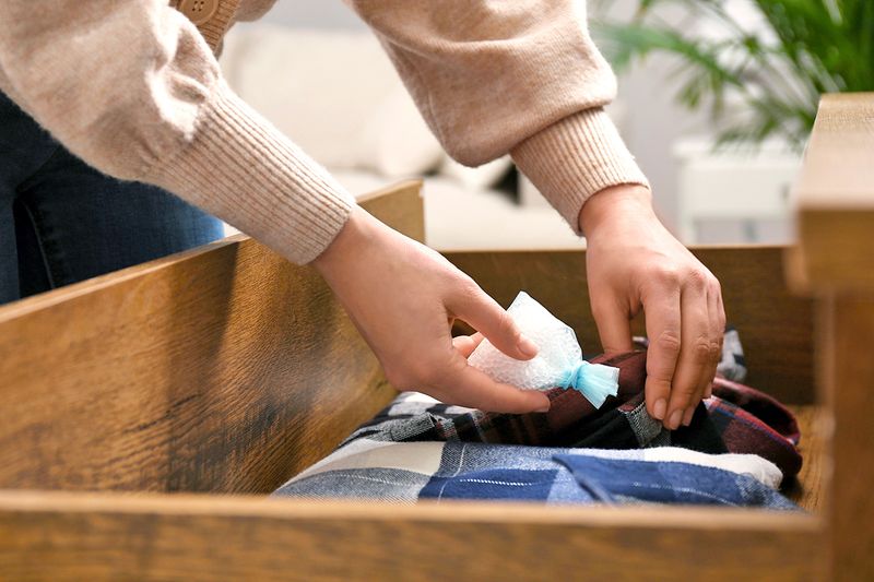 Anonymous woman adding a homemade sachets to a drawer of clothes.