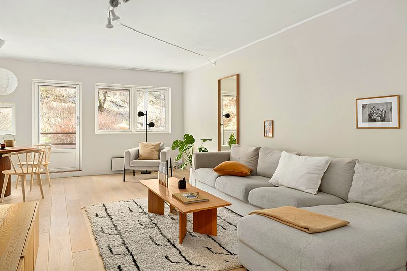 A light gray sectional in a contemporary-style living room with a coffee table, armchair, and a high-pile rug.