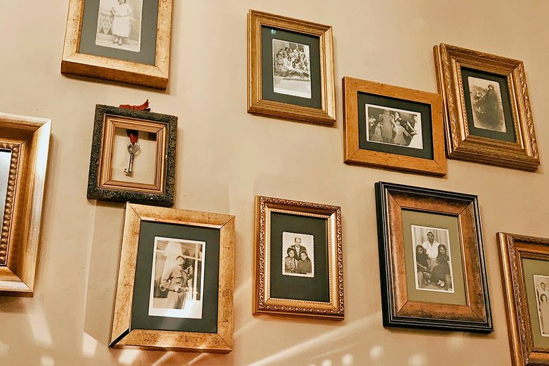 A beige-painted wall filled with framed photos of family members.