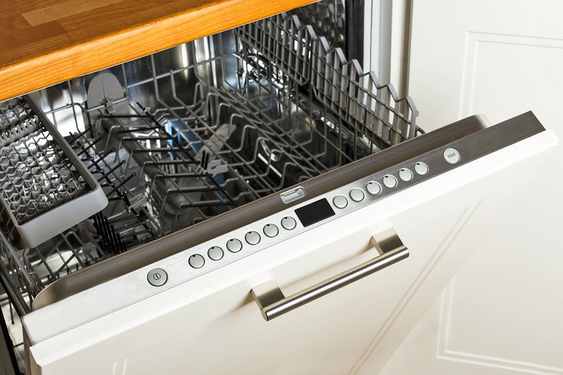 An open, paneled dishwasher revealing an empty top rack.