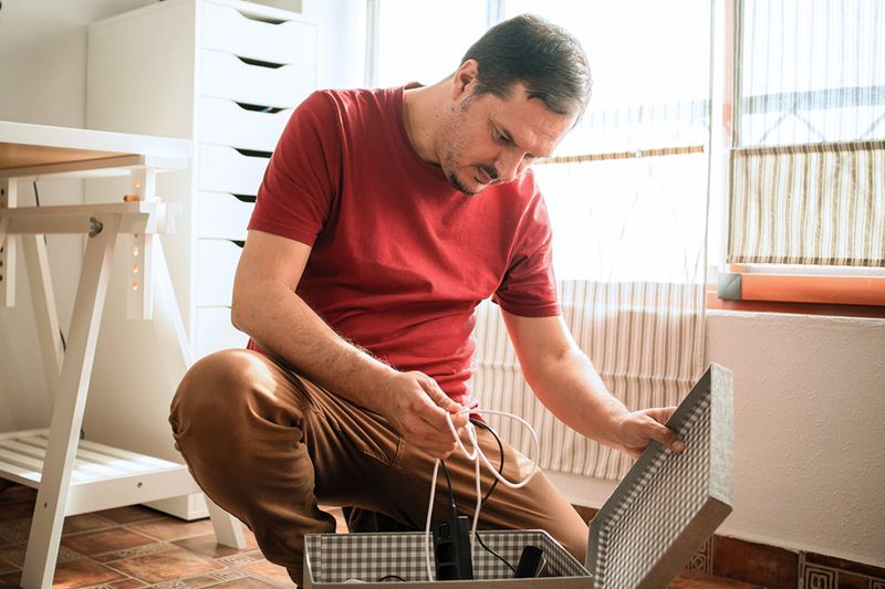 A middle-aged man going through a storage box of cables and cords.