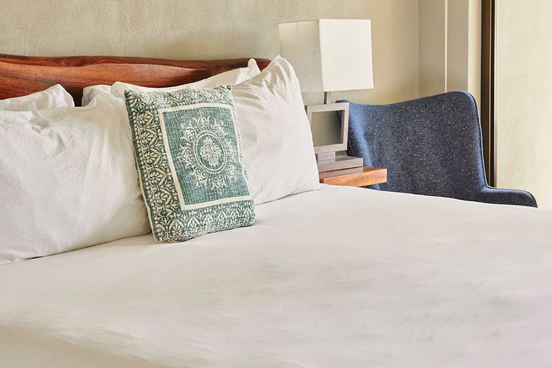A well-made bed with a wrinkle-free duvet, four bed pillows, and one decorative pillow.