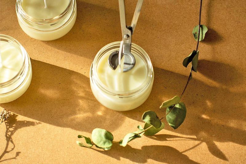 An overhead shot of a candle wick being trimmed with a wick trimmer for the first time.