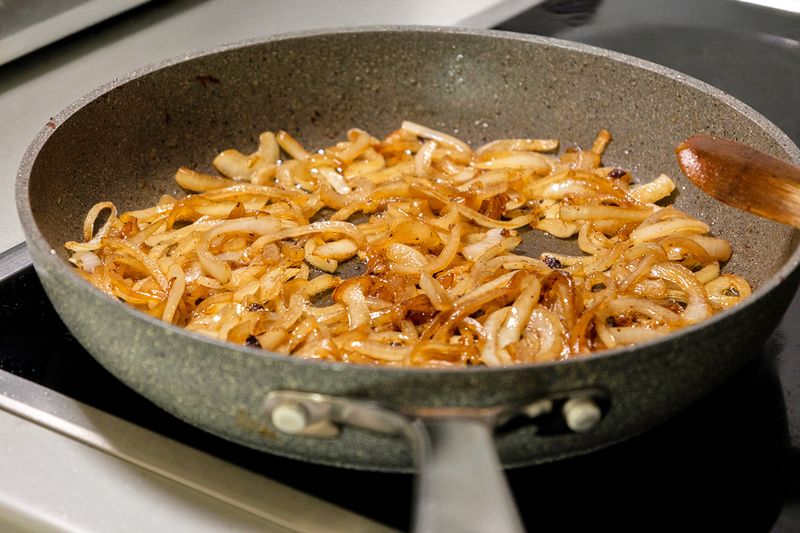 A skillet full of caramelized onions on a stovetop.