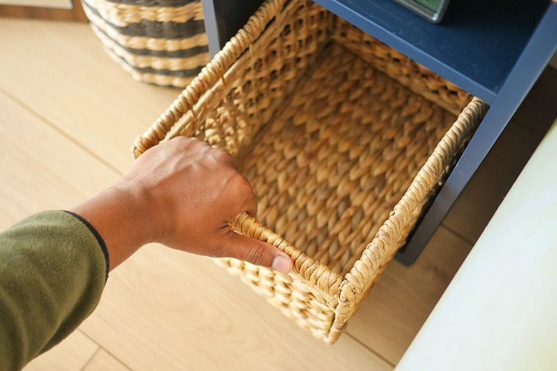 Overhead shot of an anonymous person reaching for an empty, woven storage bin.