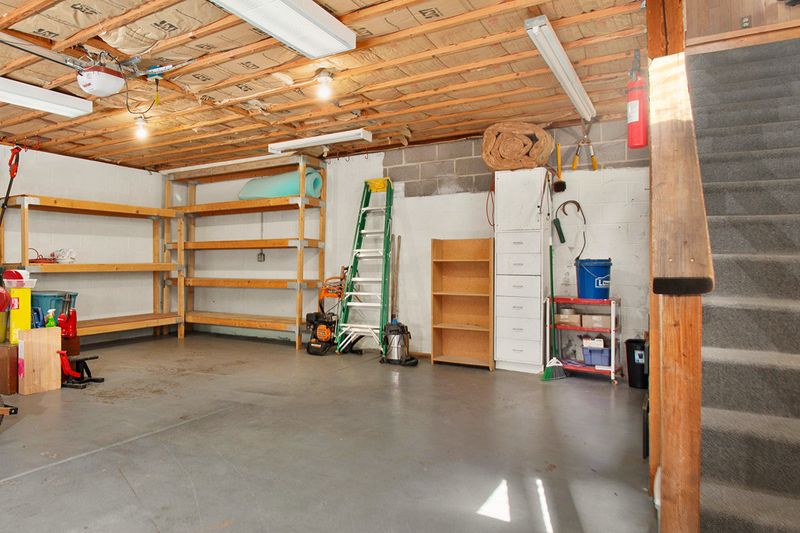 An unfinished but clean basement with a concrete floor and shelves against the walls.