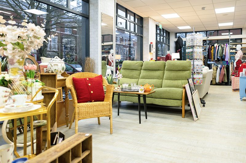 The interior of a thrift store that's displaying furniture, clothing, and home goods.