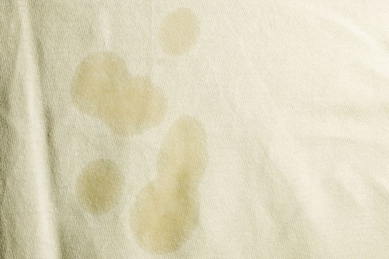 A close-up of several grease stains on off-white fabric.