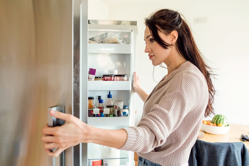 Woman standing in front of open fridge
