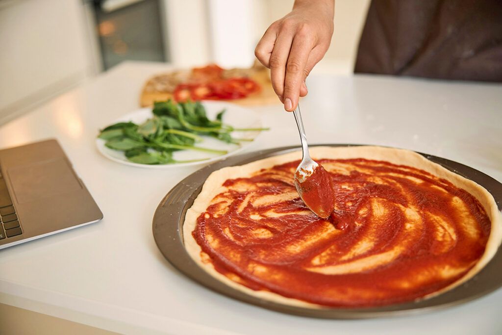 Putting sauce on homemade pizza