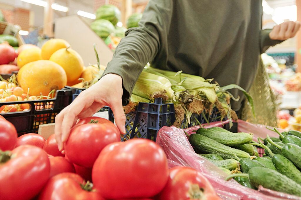 Person grabbing tomato at grocery store