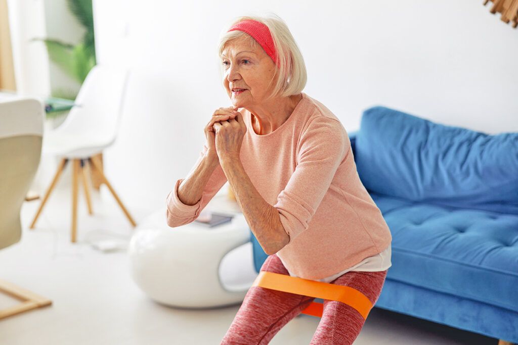 Older woman doing squat with resistance band