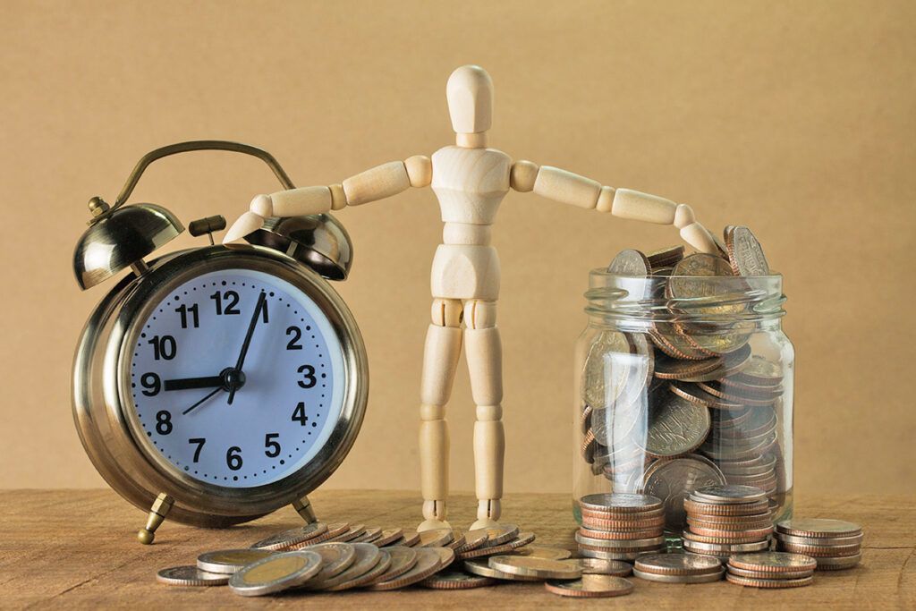 Wooden doll between alarm clock and coin jar