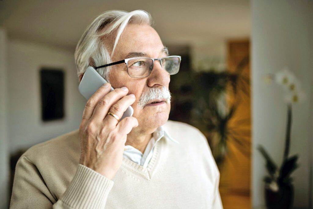 Worried older man holding cell phone