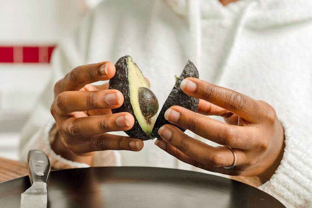 Person holding avocado sliced in half