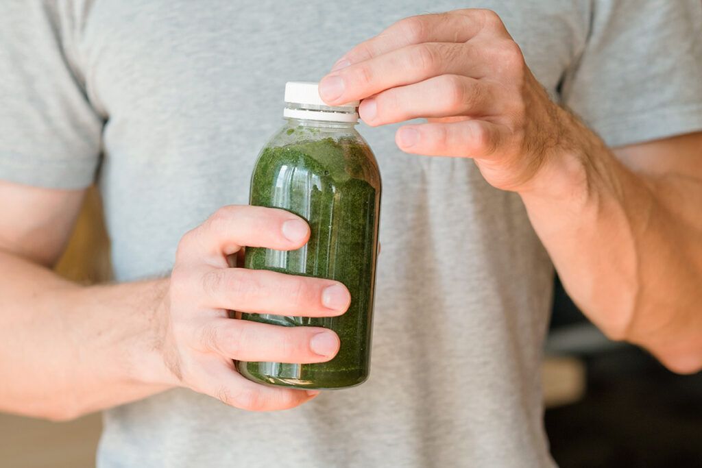Person holding bottle of green juice