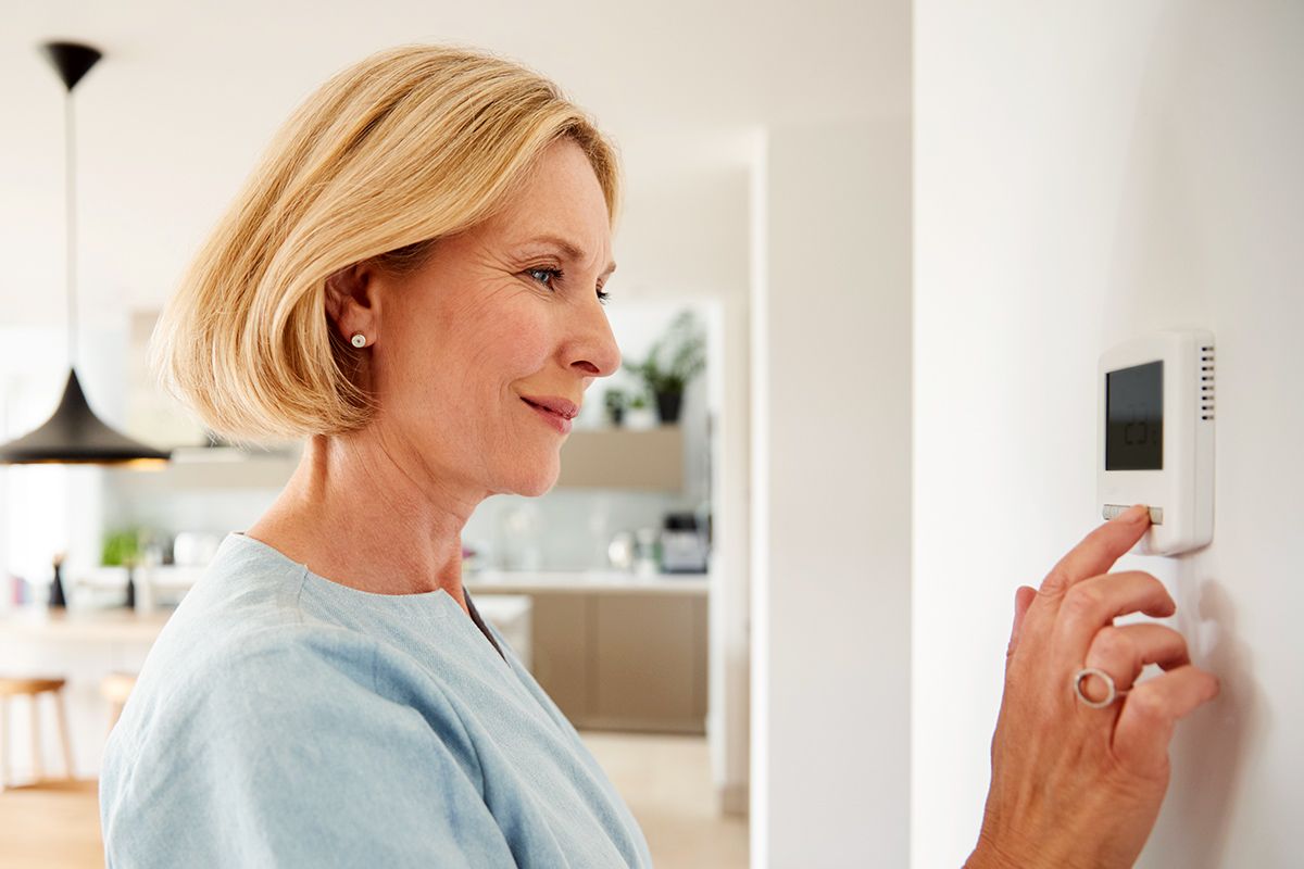 Woman setting thermostat