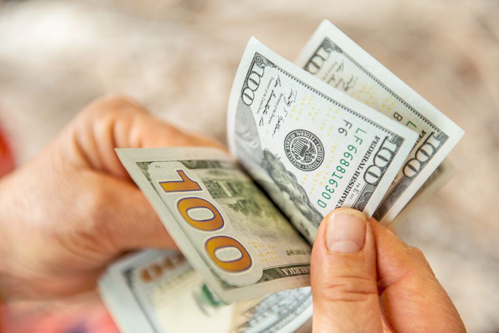 Hand holding hundred dollar bills