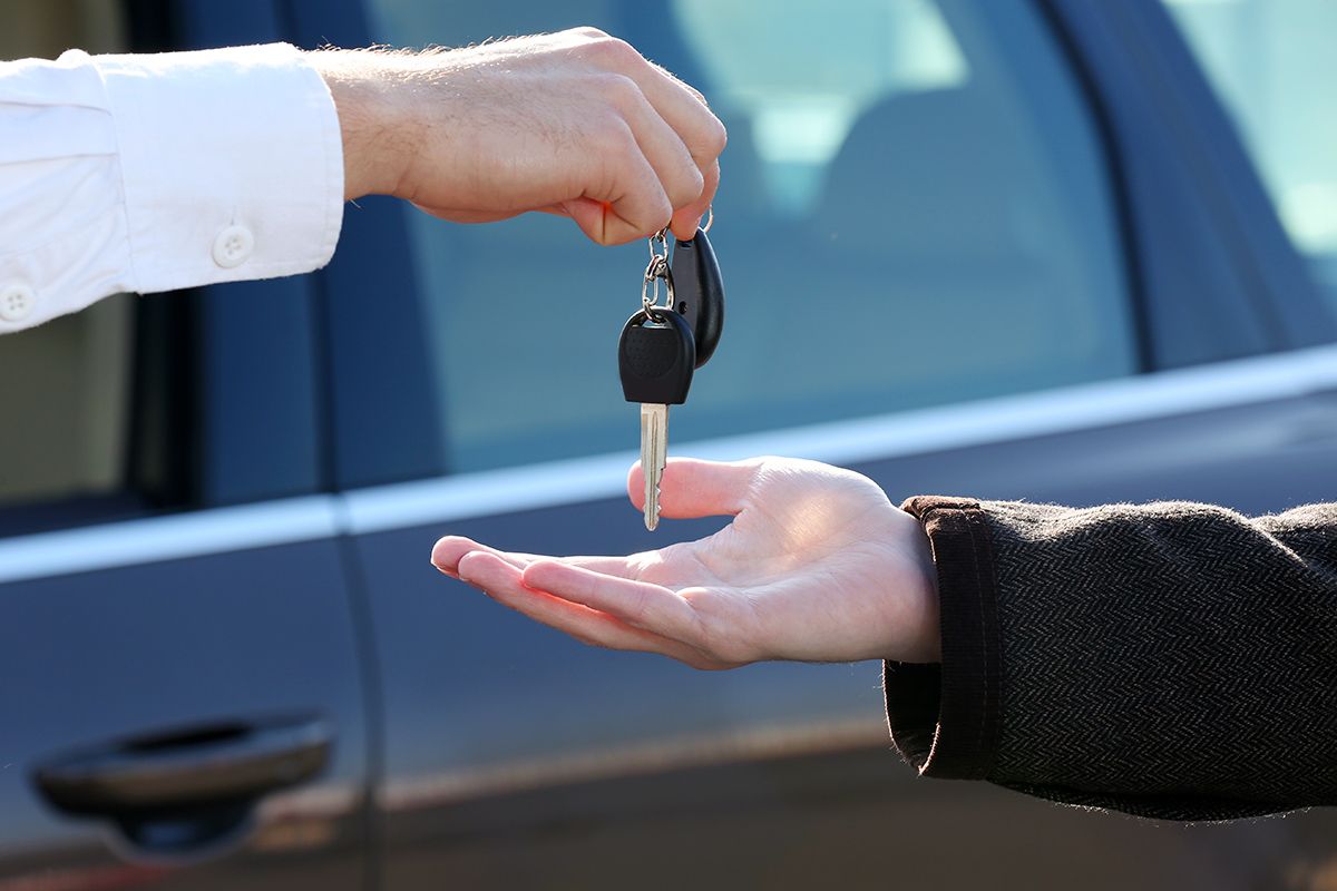 Person holding car keys out to another person