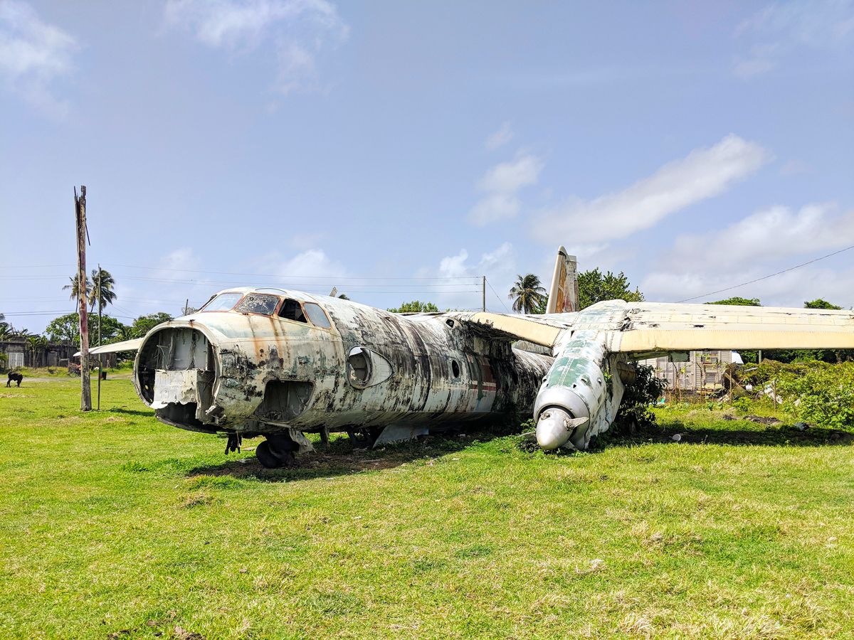 Abandoned aircraft on grassy field at Pearls Airport, Grenada