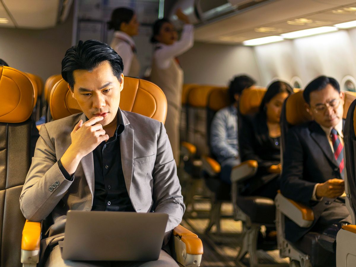 Airline passenger working on laptop in-flight