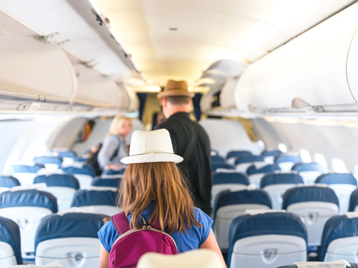 Passengers walking down airplane aisle