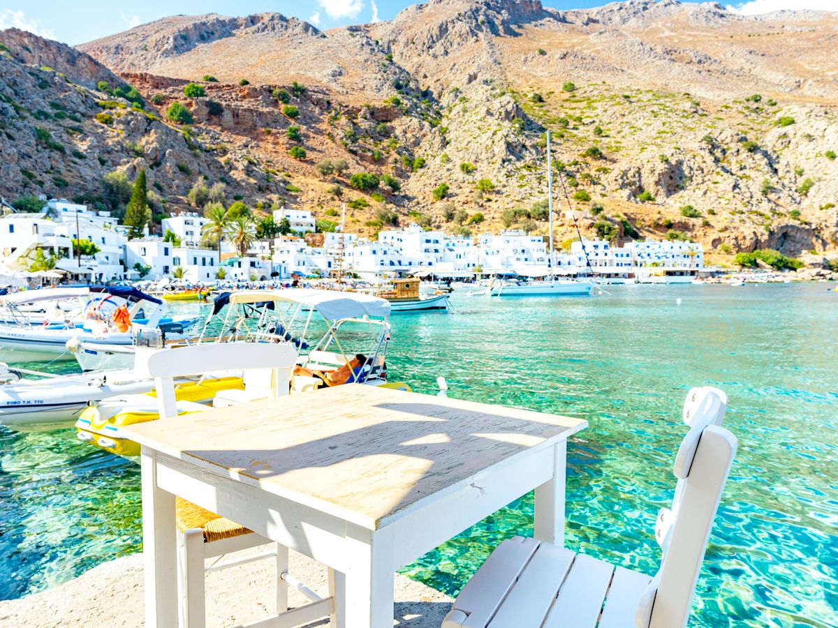 Dining table next to marina and turquoise water on the island of Crete, Grrece