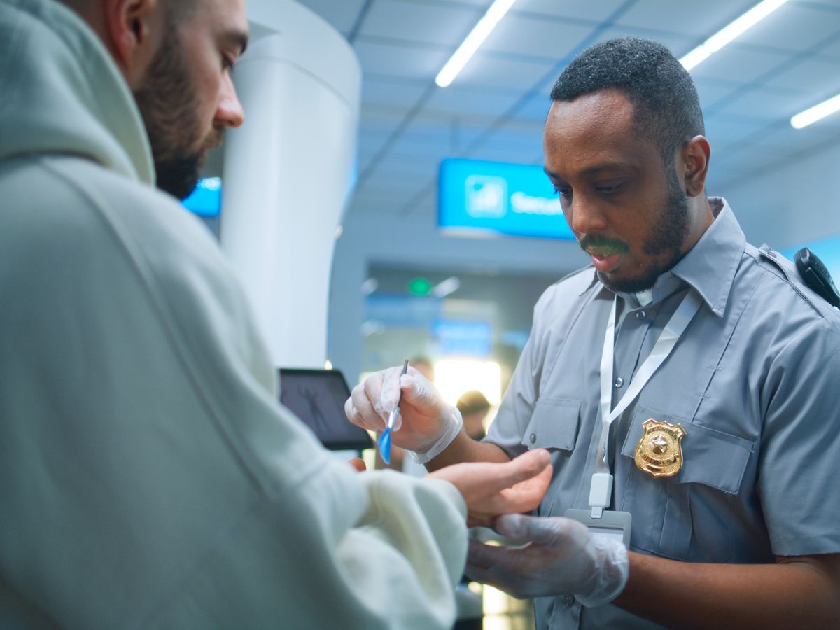 Security officer swabbing traveler's hands at checkpoint