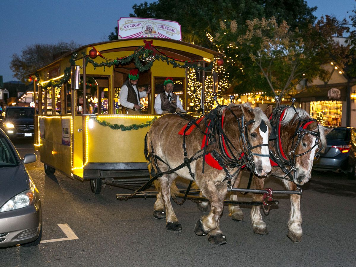 Horses pulling trolley decorated with lights in Solvang, California