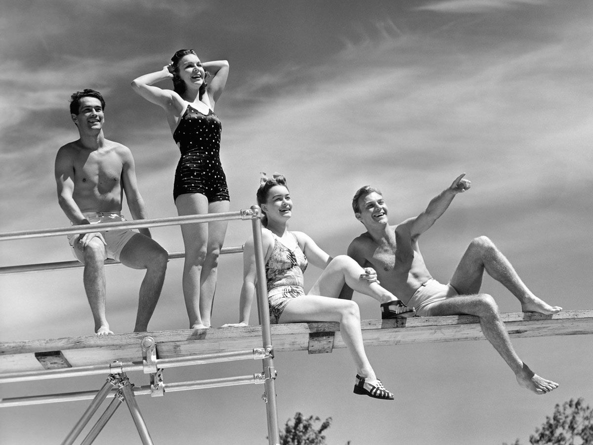 Vintage photo of young people standing on diving board in swimwear