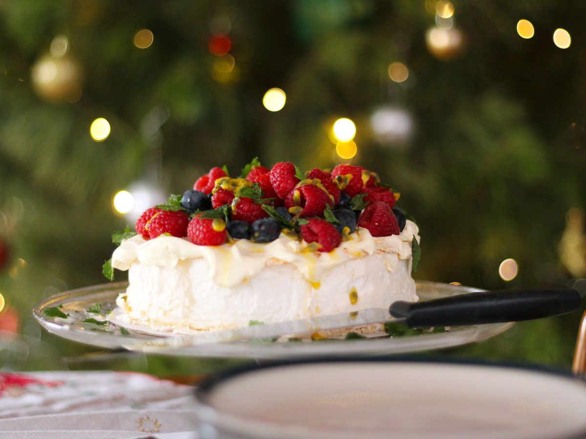 Pavlova on cake tray with Christmas tree in background