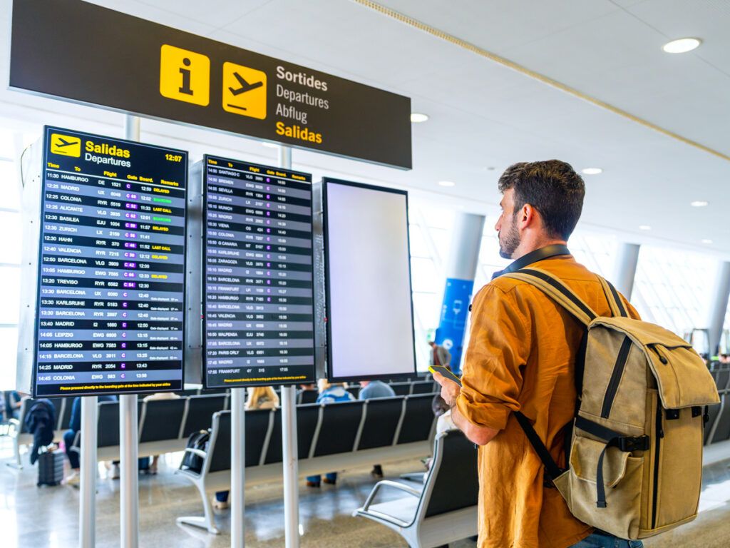 Traveler viewing flight status board in airport terminal