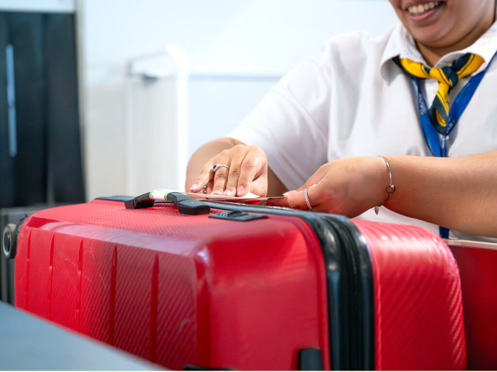 Airline agent placing tag on suitcase 
