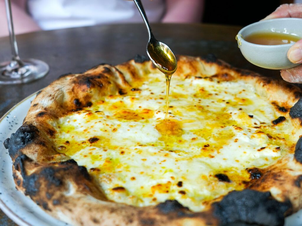 Chef spooning sauce onto Tokyo-style pizza