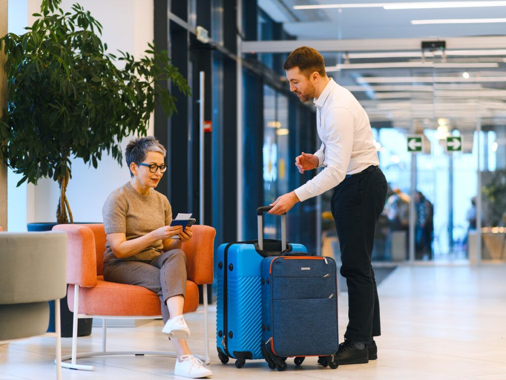 Bellhop assisting senior traveler with luggage