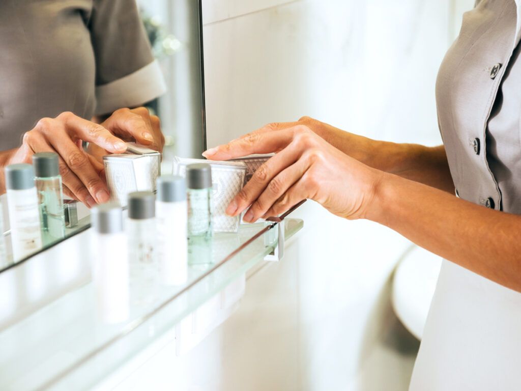 Hotel housekeeper tidying toiletries in bathroom