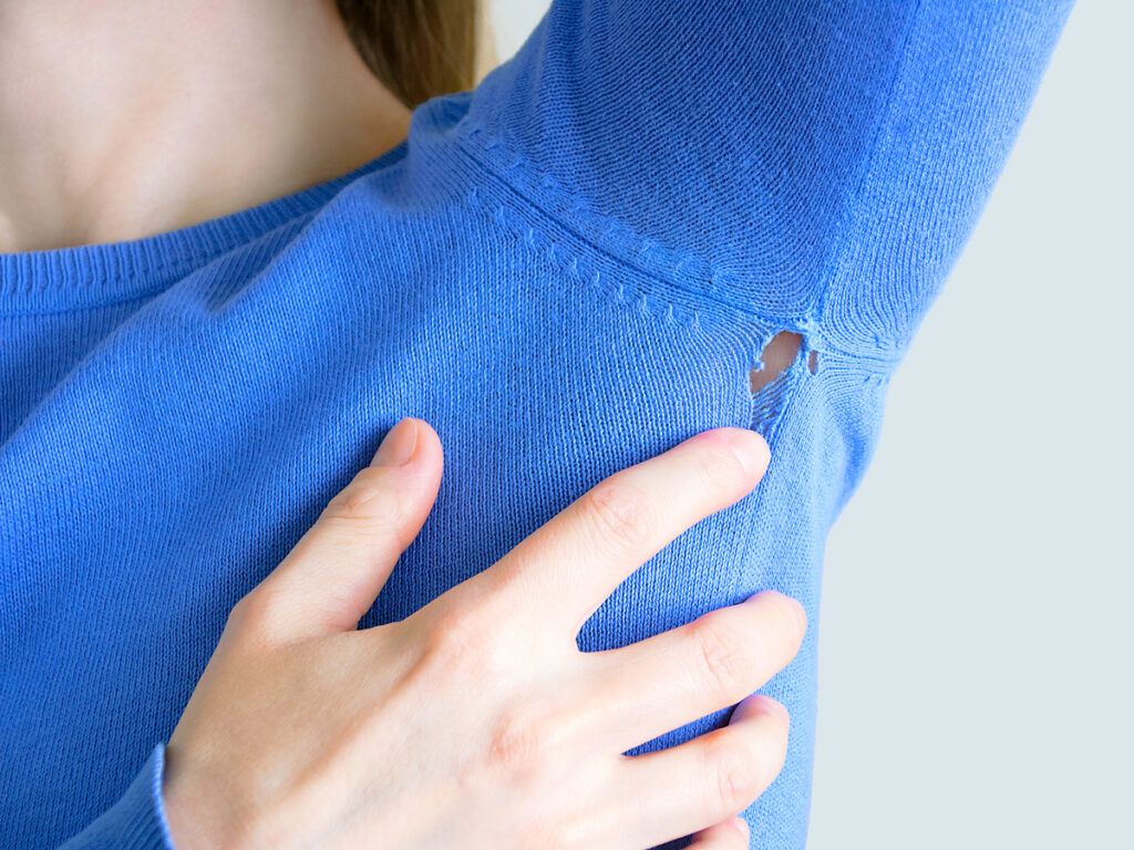 Person pointing to hole in sweater