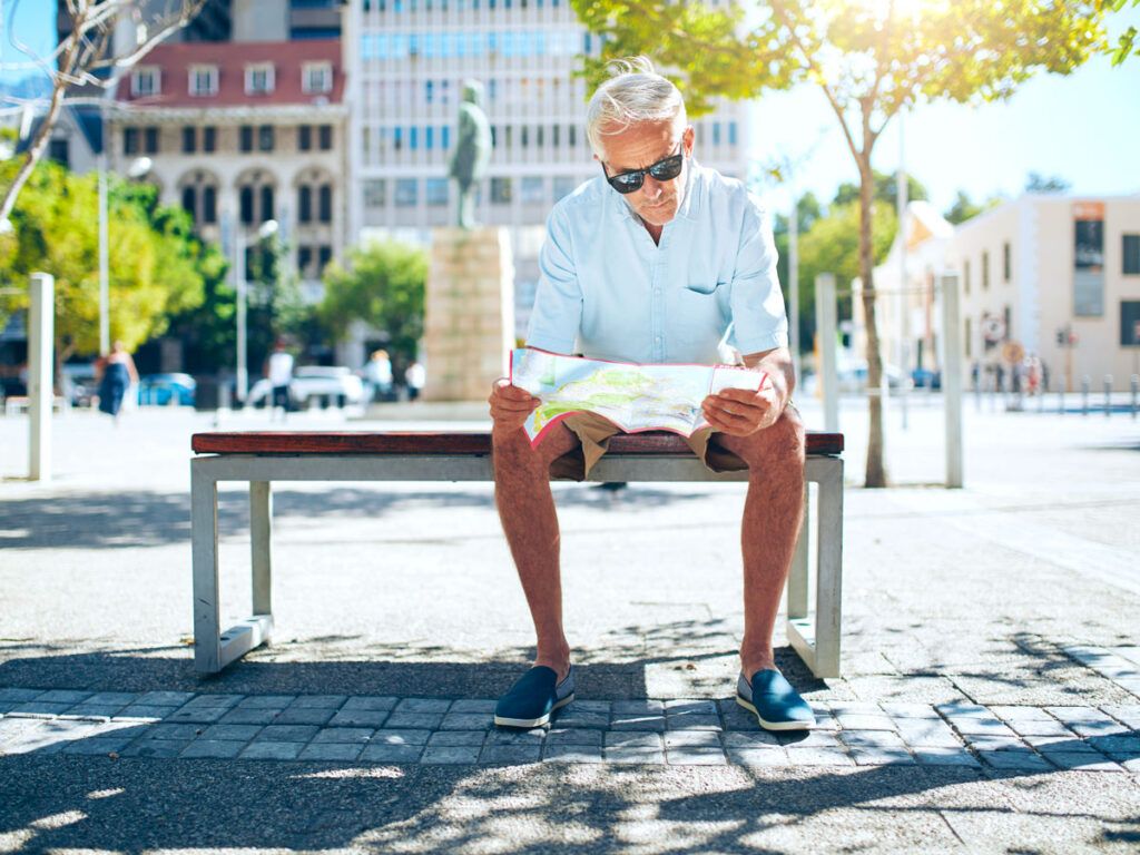 Tourist sitting on bench reading map