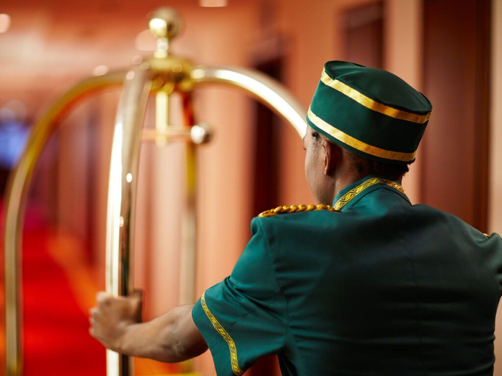 Bellhop pushing luggage cart through hotel hallway
