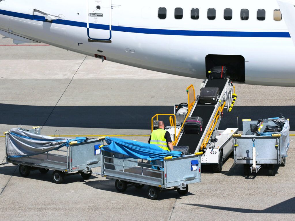 Baggage handler loading suitcases into airplane baggage hold